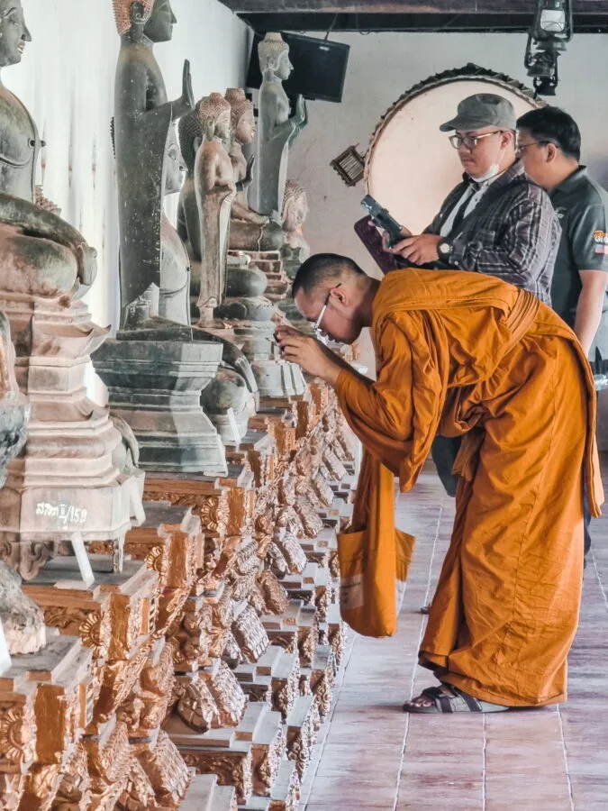 monk looking at detail statue that luang vientiane