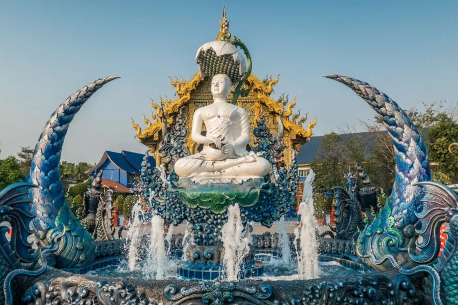 fountain with buddha in front of wat rong suea ten blue temple chiang rai