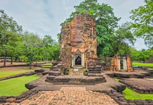 Prang khmer de Si Thep, chaussée en briques au premier plan, parc verdoyant.