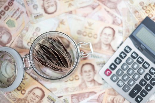 Bocal de pièces, billets thaïlandais et calculatrice