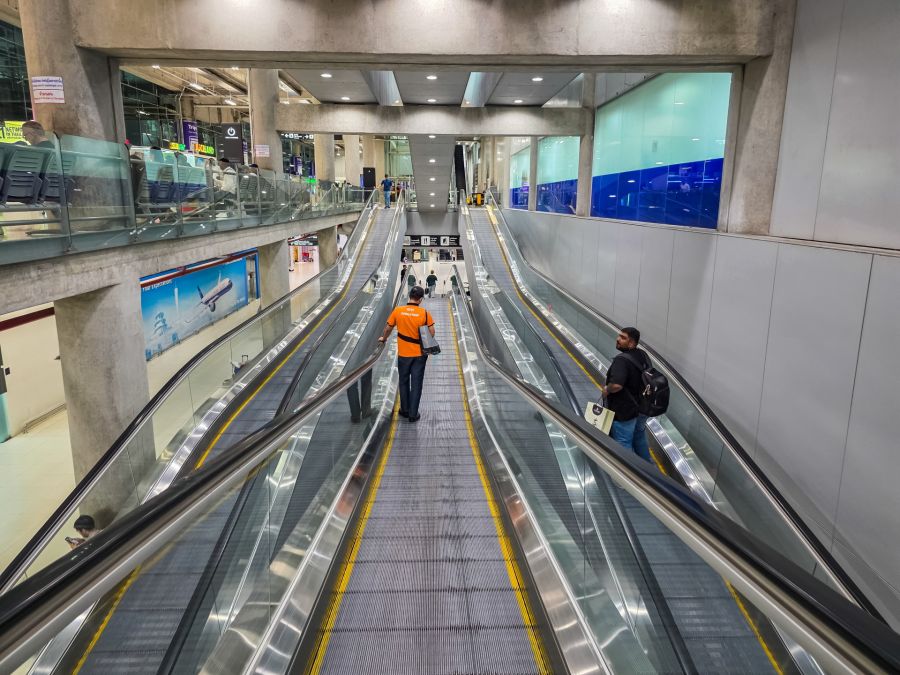 Voyageurs sur escalators dans un aéroport moderne